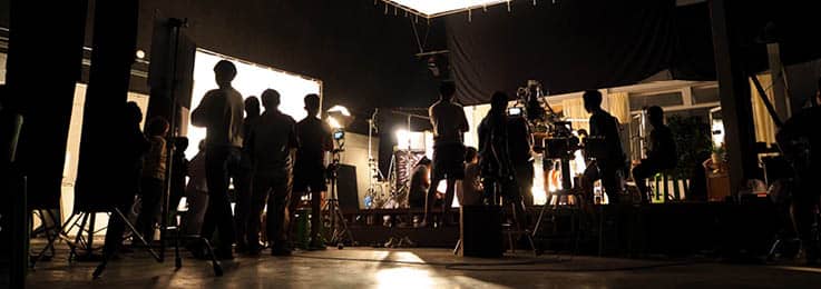 A film set crowded with members of the production crew, likely including the director or producer.